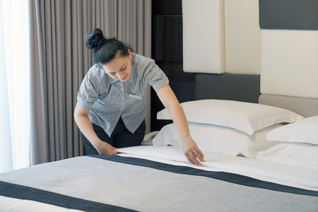 Maid making bed in hotel room. Housekeeper Making Bedの写真素材