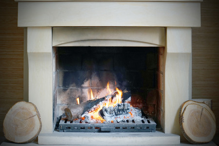 A warm fire in the stone fireplace on a cold night. Warm cozy fireplace with real wood burning in it. Cozy winter concept. Christmas and travel. Christmas backgrounds. Magic burning fireplace. Toningの写真素材
