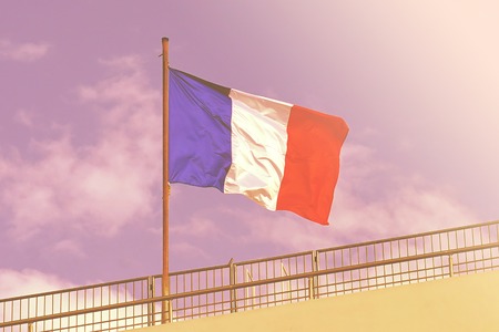 Flag of France, waving in the wind, on the blue sky. Windy flag of france against blue sky. Toning.の写真素材