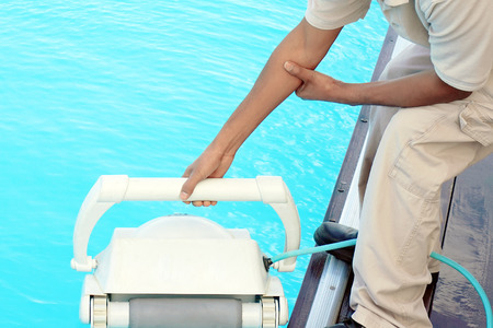 Pool cleaner during his work. Hotel staff worker cleaning the pool.の写真素材