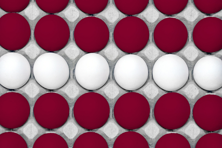 Chicken eggs painted in the style of the Latvia flag. Chicken eggs in carton box. Top view eggs...