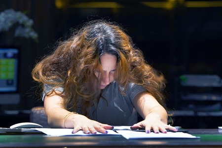 Close-up Hotel administrator. A woman-reception worker is distressed with a lot of paperwork in front of her. A lot of paper work.の写真素材