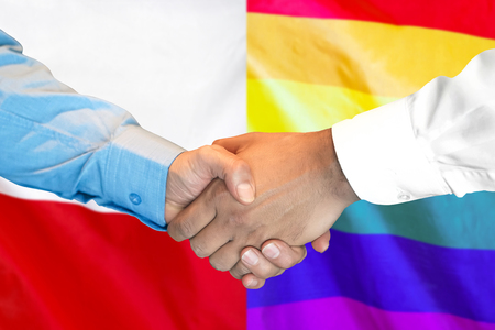 Business handshake on the background of two flags. Men handshake on the background of the Poland and LGBT gay flag. Flag of tolerance. Support conceptの写真素材