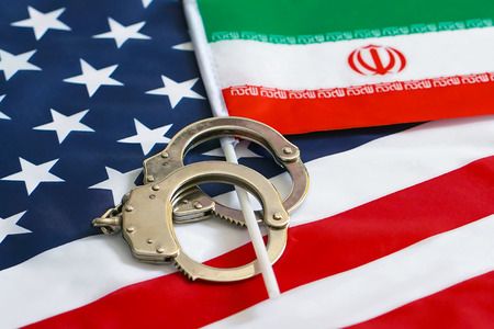 Iranian flag in handcuffs on the background of the American flag. US sanctions against Iran.の写真素材