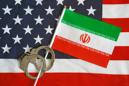 Iranian flag in handcuffs on the background of the American flag. US sanctions against Iran.の写真素材