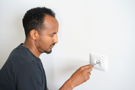 Man electrician checks the presence of electrical voltage in the socket phase. Checking the voltage...