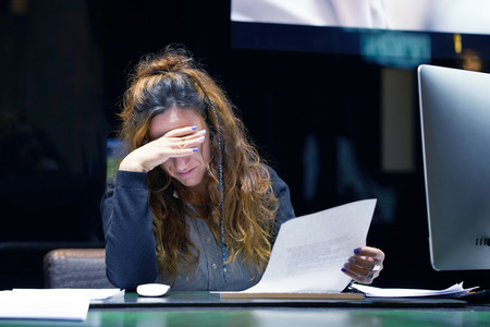 A woman-reception hotel worker reading negative news in letter. Shocked beauty girl business manager received layoff message letter from company feeling surprised. An agitated girl without joy.の写真素材