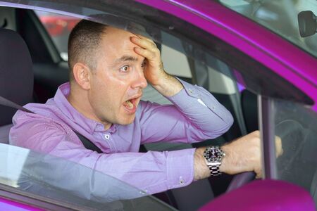 Scared funny looking young man driver in the car. Side window view of inexperienced anxious...