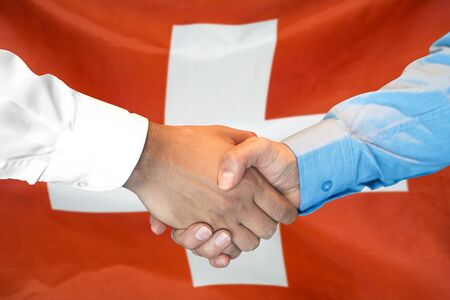 Business handshake on Switzerland flag background. Men shaking hands and Switzerland flag on background. Support conceptの写真素材