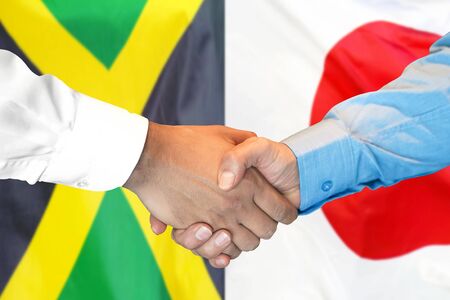 Business handshake on the background of two flags. Men handshake on the background of the Jamaica and Japan flag. Support conceptの写真素材