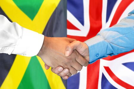 Business handshake on the background of two flags. Men handshake on the background of the Jamaica and United Kingdom flag. Support conceptの写真素材