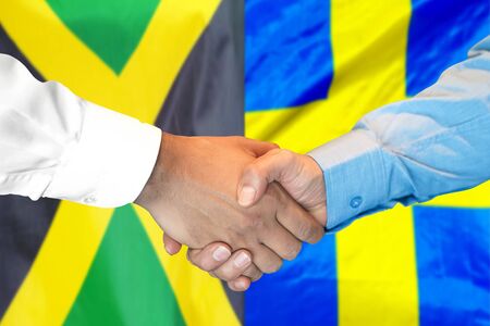 Business handshake on the background of two flags. Men handshake on the background of the Jamaica and Sweden flag. Support conceptの写真素材