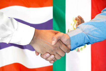 Business handshake on the background of two flags. Men handshake on the background of the Thailand and Mexico flag. Support conceptの写真素材