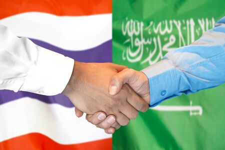 Business handshake on the background of two flags. Men handshake on the background of the Thailand and Saudi Arabia flag. Support conceptの写真素材