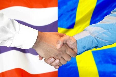Business handshake on the background of two flags. Men handshake on the background of the Thailand and Sweden flag. Support conceptの写真素材