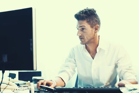 Male Working At Desk In Busy Creative Office. Office worker man at the computer. Toningの写真素材