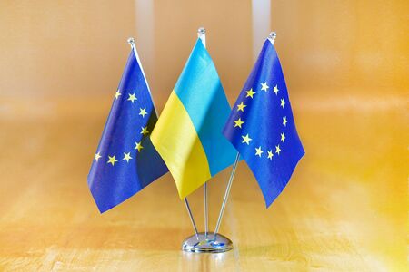 Three flags on the table. Flags of Ukraine, European Union. Flags of European Union and Ukraine on the table during a meeting of foreign ministers of European Union and Ukraine.の写真素材