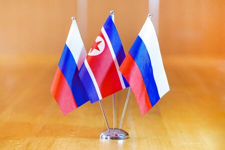 Three flags on the table. Flags of Russia and North Korea. Flags of Russia and North Korea on the table during a meeting of foreign ministers of Russia and North Korea.の写真素材