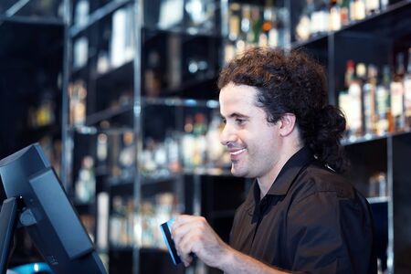 Bartender registration of a new order by a cash register. The barman pays the order with a credit card. Service concept.の写真素材