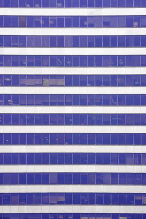 Glass blue Windows of facade modern city business building skyscraper. Modern apartment buildings in new neighborhood. Windows of a building, texture.の写真素材