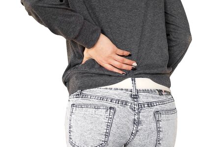 Woman with pain in kidneys isolated on white background.  Young woman with back ache clasping her hand to her lower back. Woman suffering from ribbing pain, waist pain. Body Concept.の写真素材