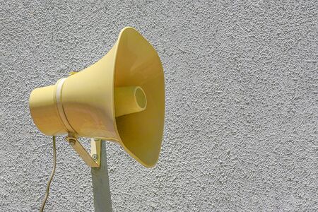 Yellow plastic Loudspeaker on the street on wall. The siren of air alarm.の写真素材