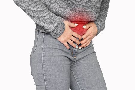 Closeup view of  woman hand in gray jeans having painful stomachache isolated on a white background. Chronic gastritis. Body And Health Care Concept.の写真素材