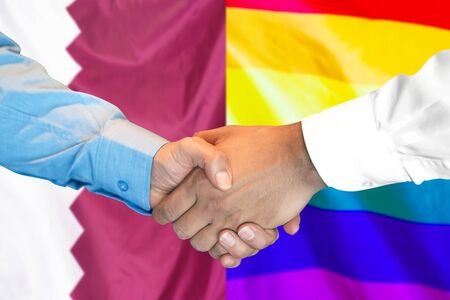 Business handshake on the background of two flags. Men handshake on the background of the Qatar and LGBT gay flag. Support conceptの写真素材