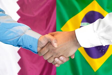 Business handshake on the background of two flags. Men handshake on the background of the Qatar and Brazil flag. Support conceptの写真素材