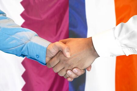 Business handshake on the background of two flags. Men handshake on the background of the Qatar and France flag. Support conceptの写真素材