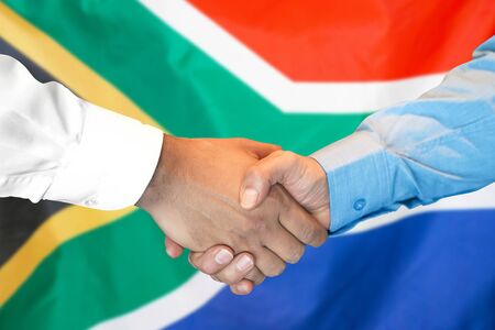 Business handshake on South Africa flag background. Men shaking hands and South Africa flag on background. Support conceptの写真素材