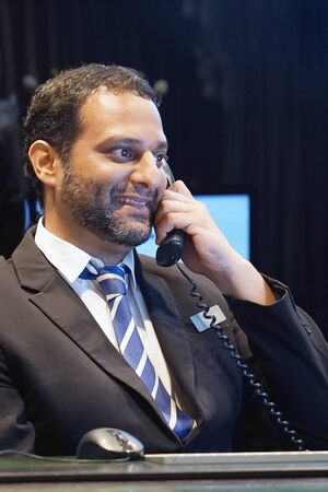 Businessman talking on phone at work. Close-up a male office worker answering the phone and looking...