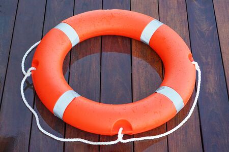 Orange lifebuoy on the wooden floor of the swimming pool                               の写真素材