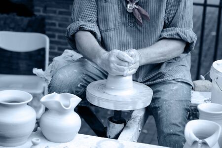Close-up hands male creating cans or vases of gray clay. Man's hands make a clay pitcher, macro. Potter makes a pitcher.の写真素材