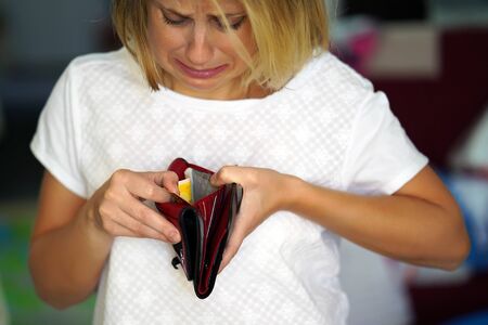 Unhappy woman holding an empty wallet. Young caucasian woman with empty wallet.の写真素材