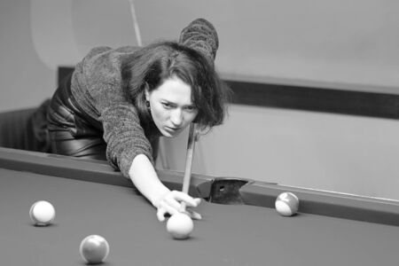 Black and white image of a girl playing snooker. Young happy woman having fun with billiard.の写真素材