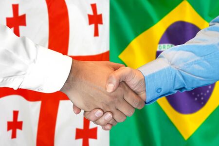 Business handshake on the background of two flags. Men handshake on the background of the Georgia and Brazil flag. Support conceptの写真素材