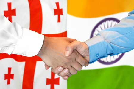Business handshake on the background of two flags. Men handshake on the background of the Georgia and India flag. Support conceptの写真素材