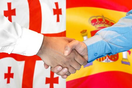 Business handshake on the background of two flags. Men handshake on the background of the Georgia and Spain flag. Support conceptの写真素材
