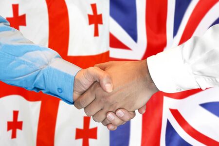 Business handshake on the background of two flags. Men handshake on the background of the Georgia and United Kingdom flag. Support conceptの写真素材