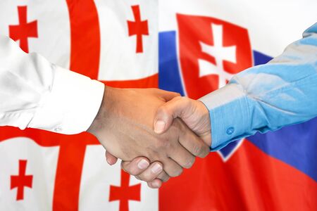Business handshake on the background of two flags. Men handshake on the background of the Georgia and Slovakia flag. Support conceptの写真素材
