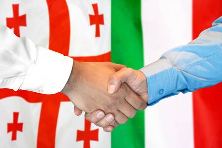 Business handshake on the background of two flags. Men handshake on the background of the Georgia and Italy flag. Support conceptの写真素材