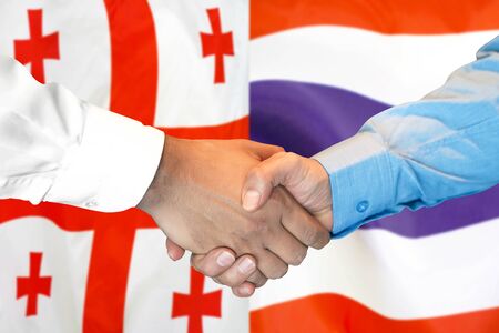 Business handshake on the background of two flags. Men handshake on the background of the Georgia and Thailand flag. Support conceptの写真素材