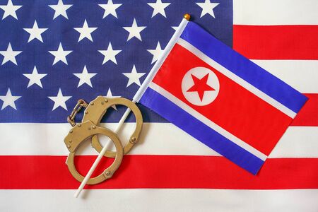 North Korea flag in handcuffs on the background of the American flag. US sanctions against North Korea.の写真素材