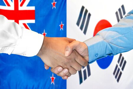 Business handshake on the background of two flags. Men handshake on the background of the New Zealand and South Korea flag. Support conceptの写真素材