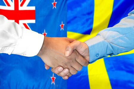 Business handshake on the background of two flags. Men handshake on the background of the New Zealand and Sweden flag. Support conceptの写真素材
