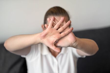 Woman hide her face at hand. Woman holding her hand stretched out toward the camera, covering her...