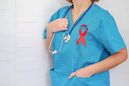Wonan doctor with a stethoscope on shoulder holding red ribbon HIV, world AIDS day awareness ribbon....