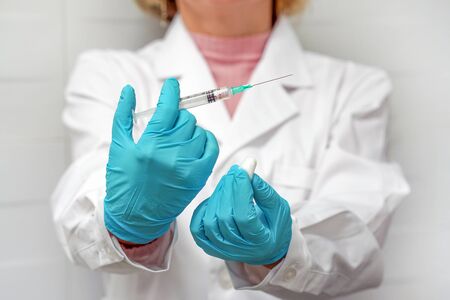 Closeup of female doctor holding syringe with medical cotton wool. Woman doctor with syringe ready...