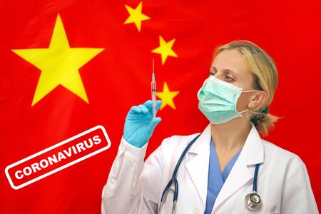 Portrait of female doctor or nurse in blue gloves holding syringe for vaccination and looking at the camera against the Chinese flag.の写真素材